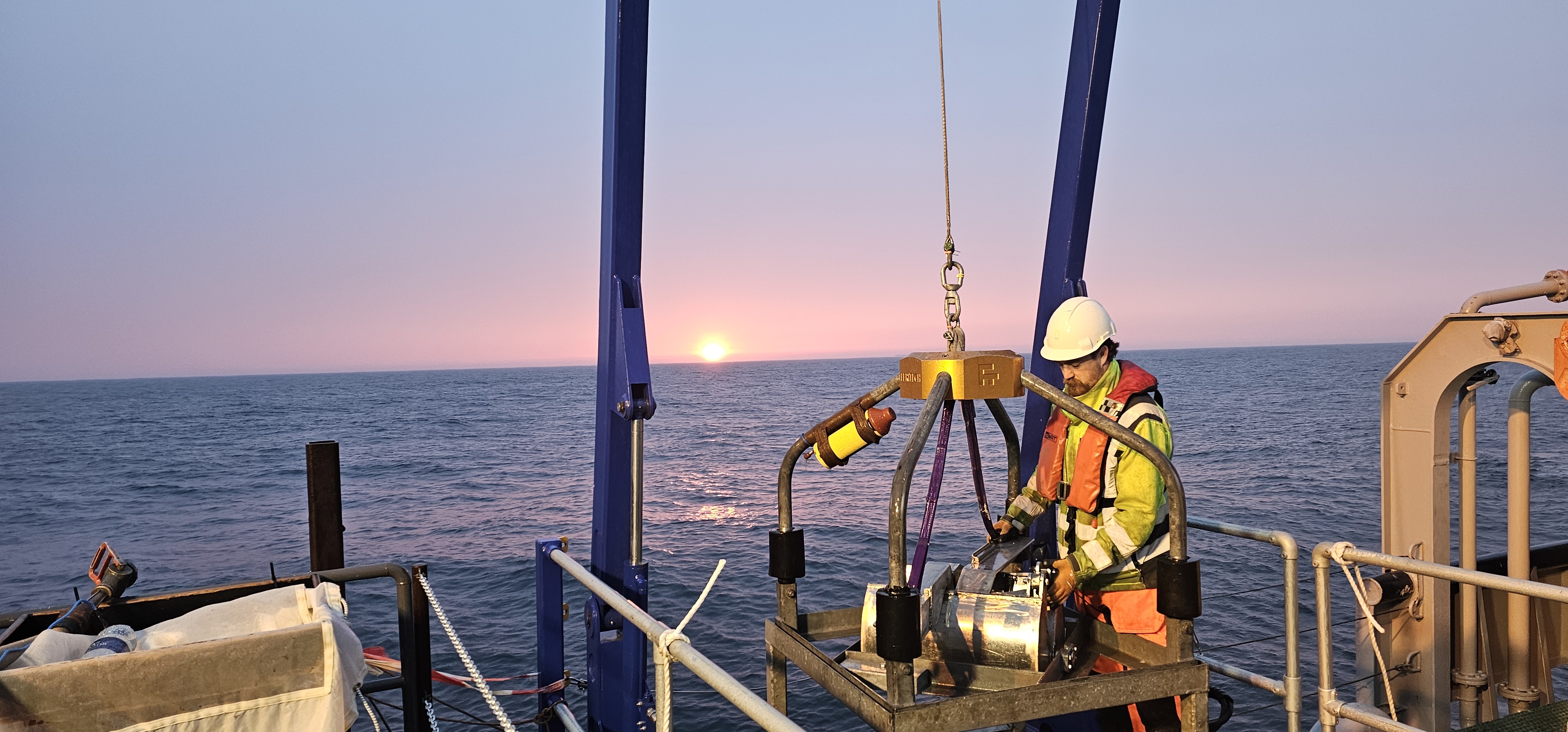 Survey engineer deploying equipment offshore at sunset